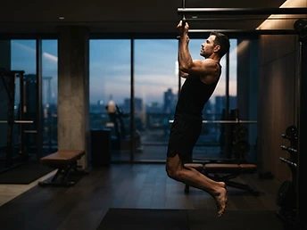 Fit man in a minimal gym at dawn in moody light