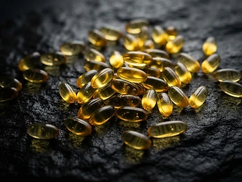 Golden softgel capsules on dark stone