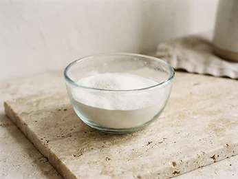 White powder in a glass bowl on travertine