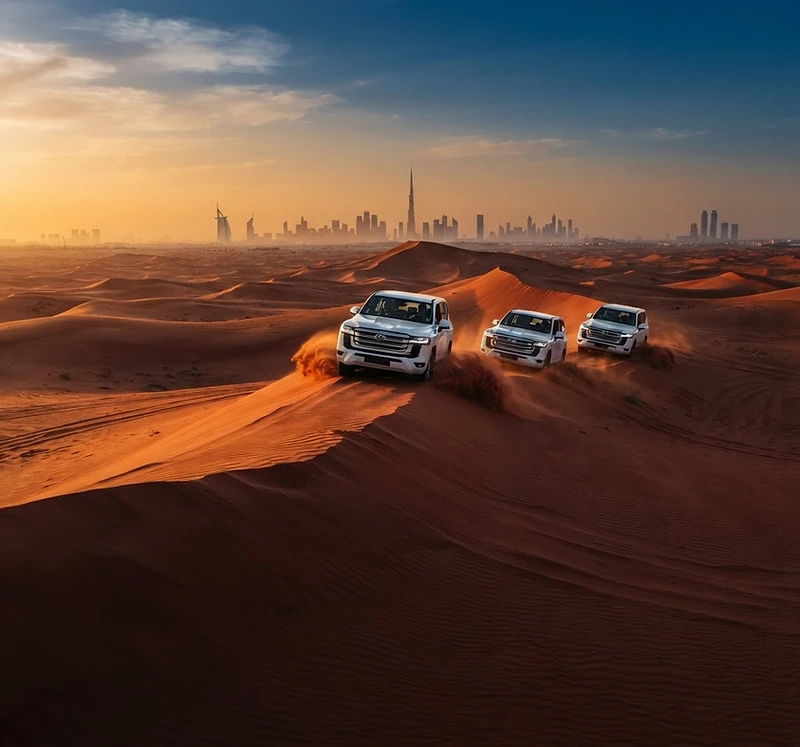 Land Cruisers crossing red dunes at sunset with the Dubai skyline on the horizon