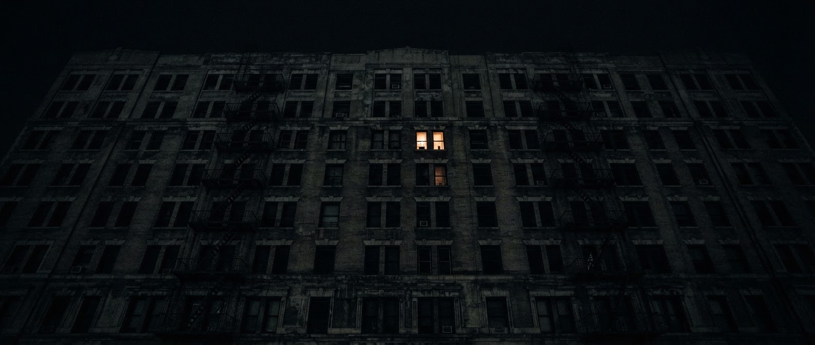Una finestra illuminata in un palazzo buio di notte
