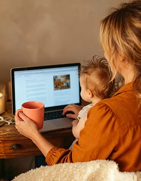 Madre trabajando desde casa con su bebé en el regazo