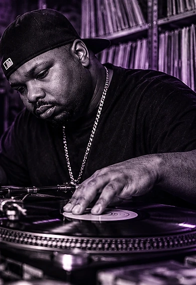 DJ working at a turntable in a dark music studio; conceptual tribute image.