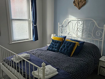 The bed made up with patterned linen and blue cushions