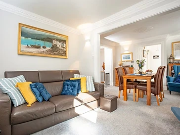 The sunlit lounge, with a leather sofa, opening onto the dining room