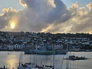 A naval patrol ship moored in the Dart at sunset
