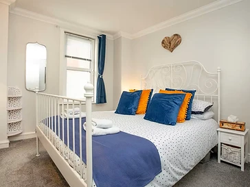 The king-size bedroom, dressed in navy and marigold