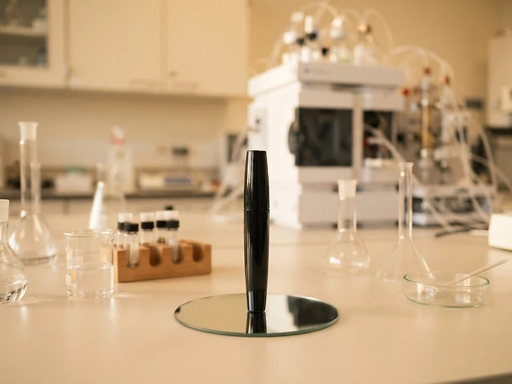 Laboratory bench with glassware and an unlabeled black mascara tube