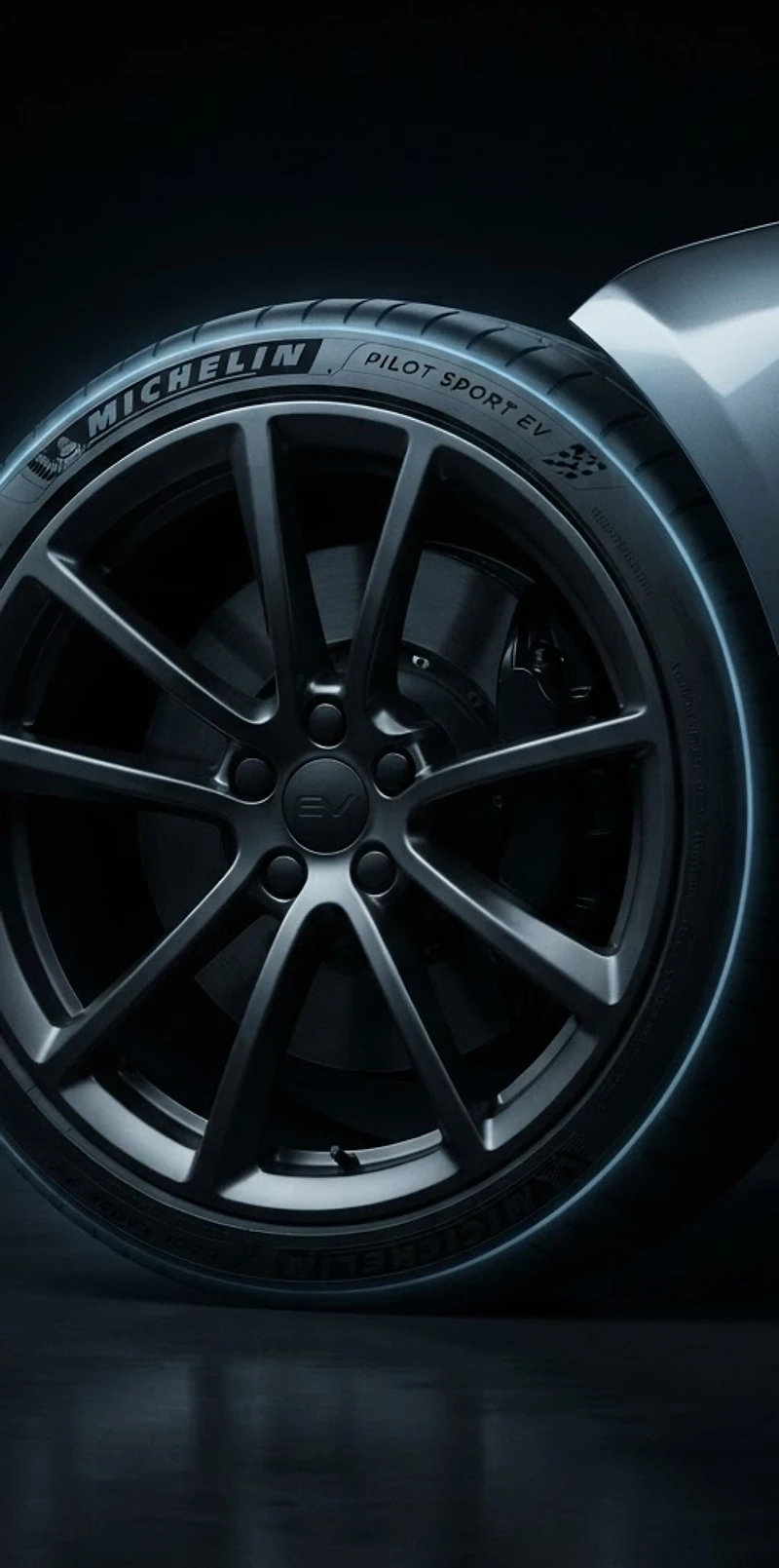 Modern EV wheel and tire in a dark studio with blue rim light