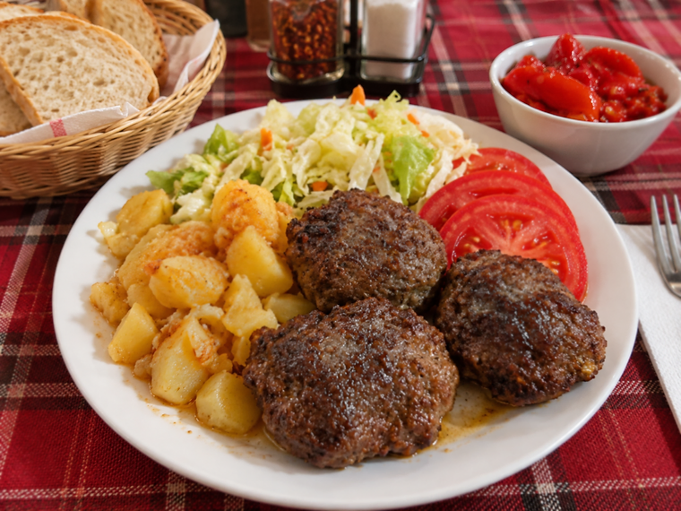 Пържени кюфтета с печени картофи, зеле и моркови и домати върху карирана покривка