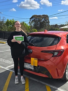 A happy Green Signals Driving School student holding their VicRoads congratulations certificate after passing at Mitcham.