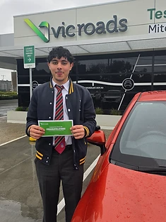 A happy Green Signals Driving School student holding their VicRoads congratulations certificate after passing at Mitcham.