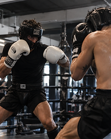 Dos luchadores haciendo sparring con guantes y protecciones