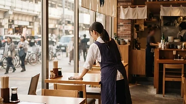 駅前の飲食店でテーブルを拭くスタッフの後ろ姿