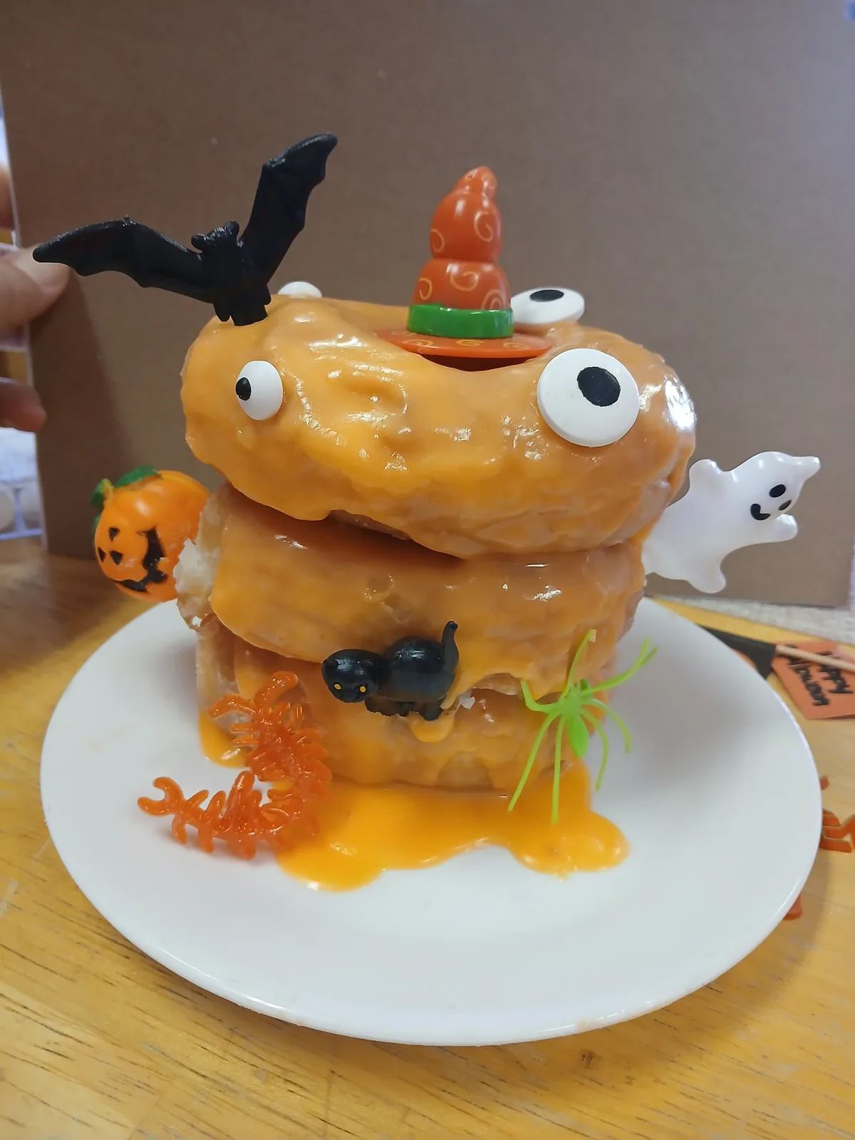 A stacked Halloween treat donut topped with a bat and a candy corn