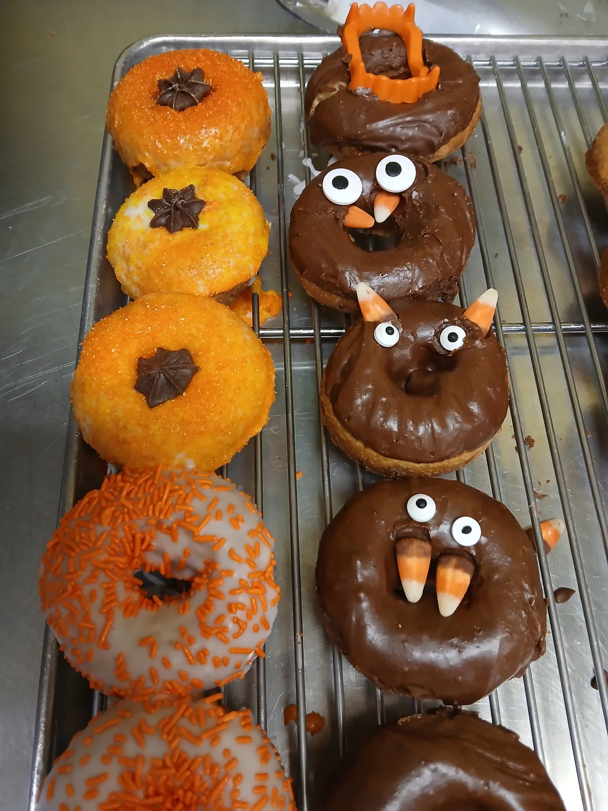 A row of pumpkin and owl donuts cooling on the rack