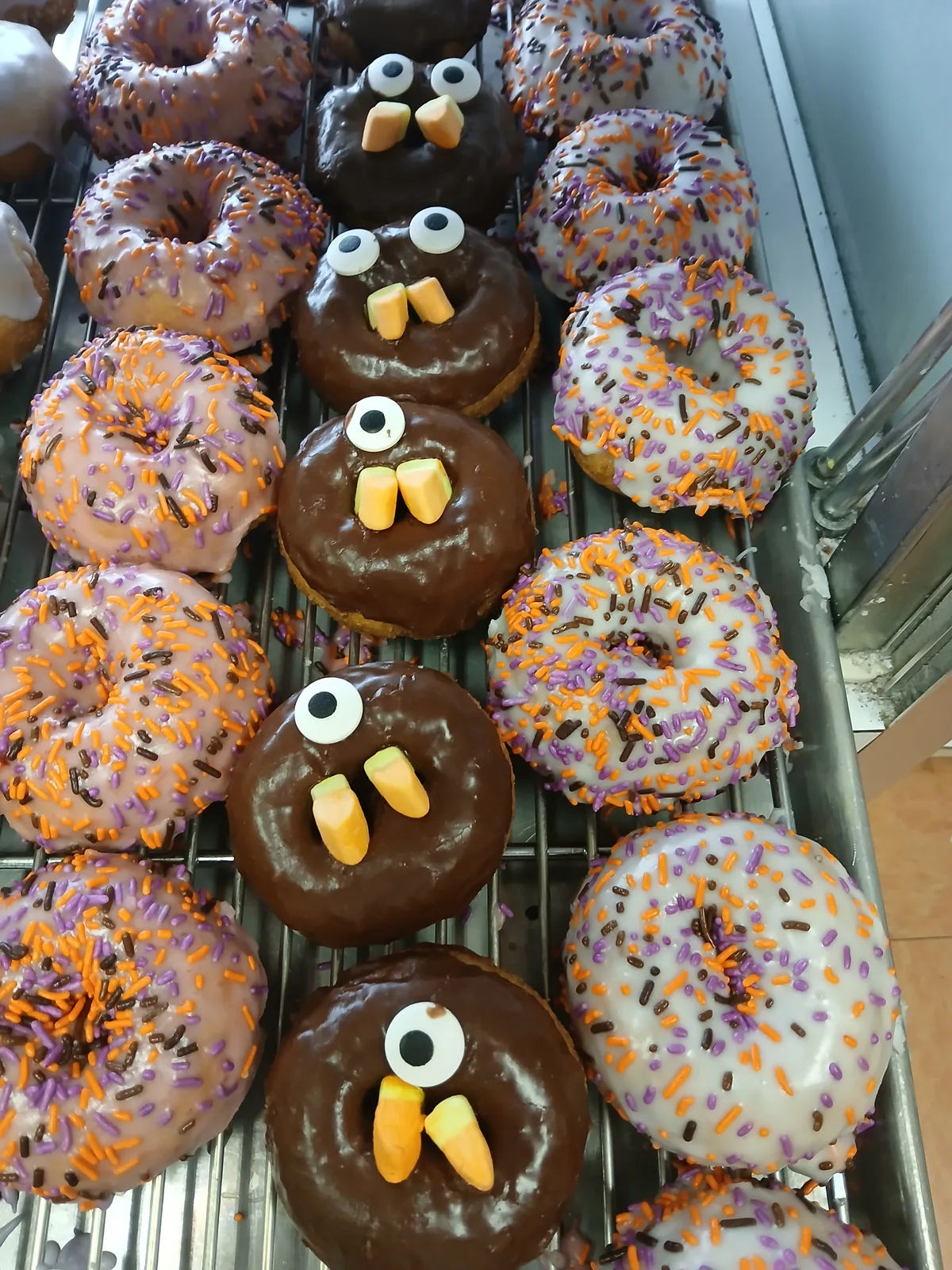 Trays of Halloween donuts with candy corn fangs and candy eyes