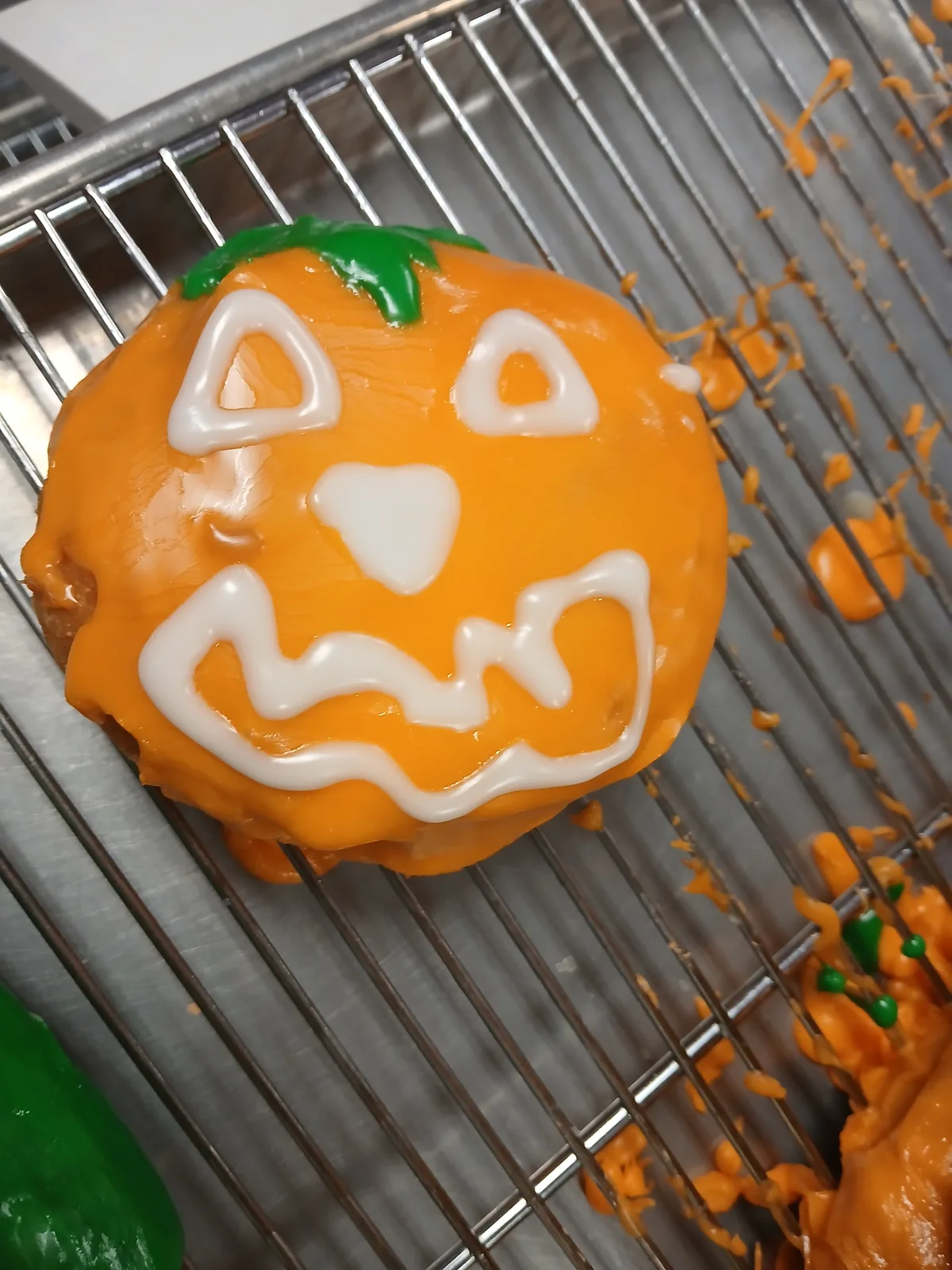 A single jack-o-lantern donut iced orange with a carved pumpkin face
