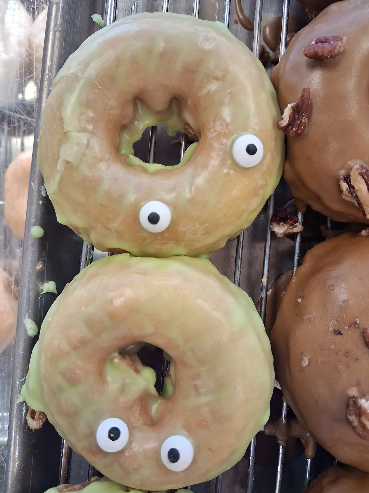 Two glazed donuts decorated with candy eyes