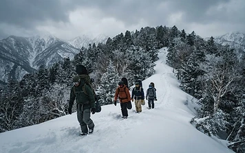 Guide leading snowboarders up a snowy ridge