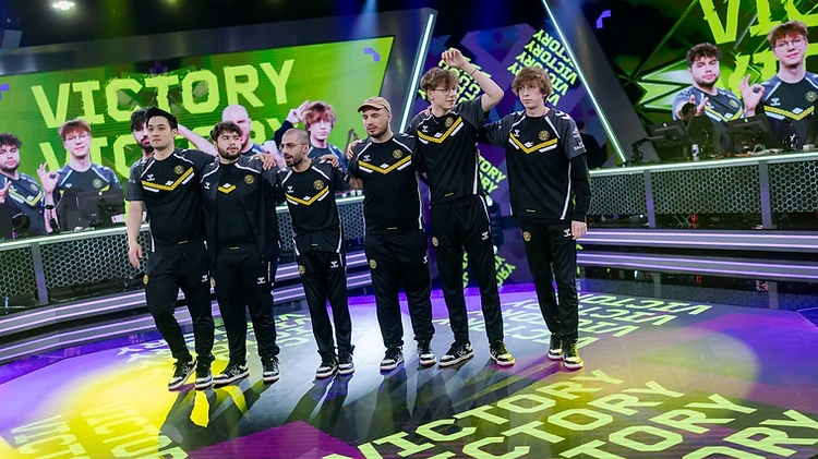 Players in black and gold kits celebrate on stage with VICTORY lit up on the screen behind them.