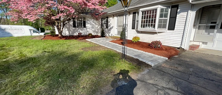 Freshly installed stone walkway with mulch beds and a blooming dogwood at a landscaped Marlborough home