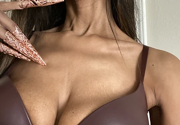 Rose-gold claw jewelry raised against leather — detail of the hand