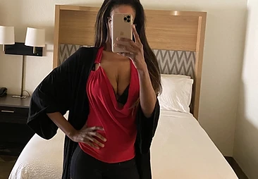 Hotel mirror study in red cowl neck and black, gold phone in hand
