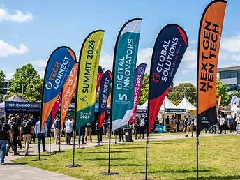 Custom printed feather and teardrop event flags lined up at an outdoor promotional event