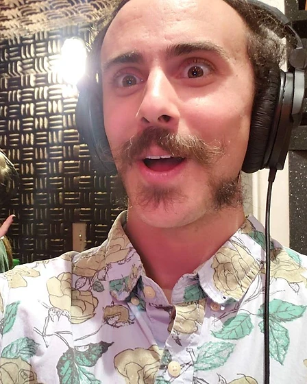 Fish in a recording studio with acoustic foam panels, alongside another person