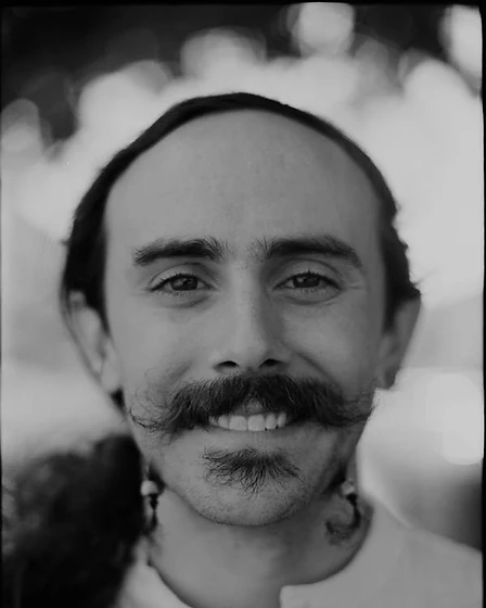 Black-and-white portrait of Fish smiling, with his distinctive handlebar mustache
