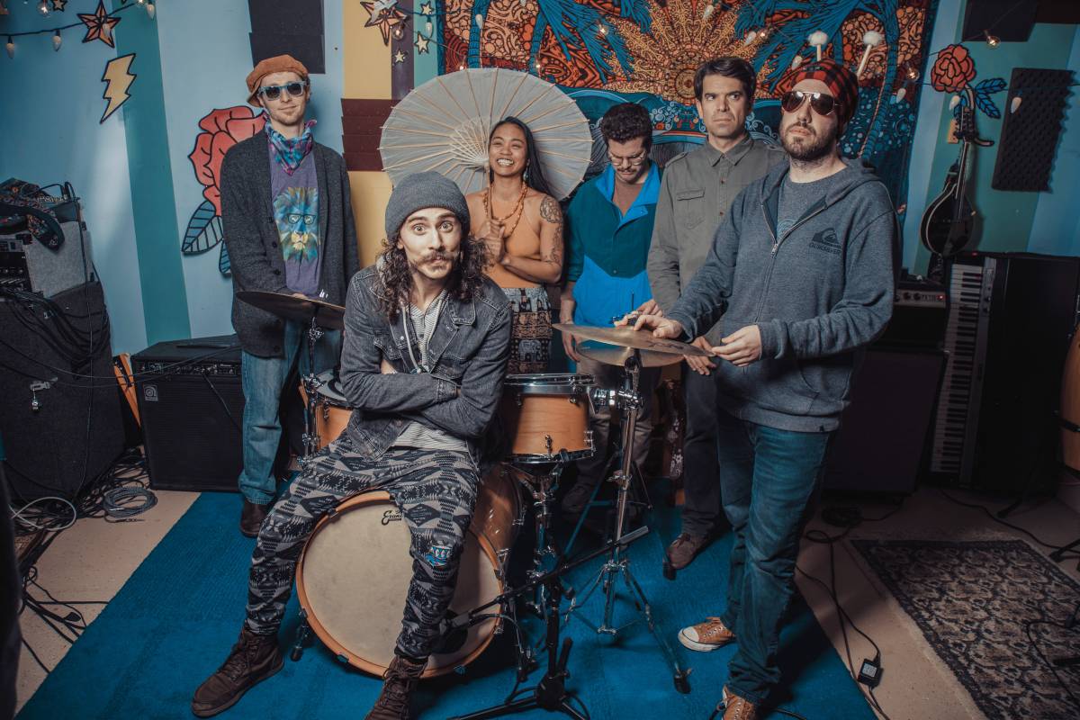 The full band posing together inside a colorful studio room
