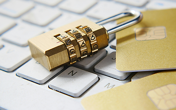 A combination padlock beside a payment card on a computer keyboard.