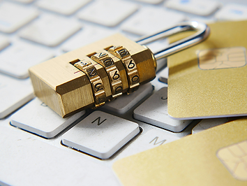 A combination padlock beside a payment card on a computer keyboard.