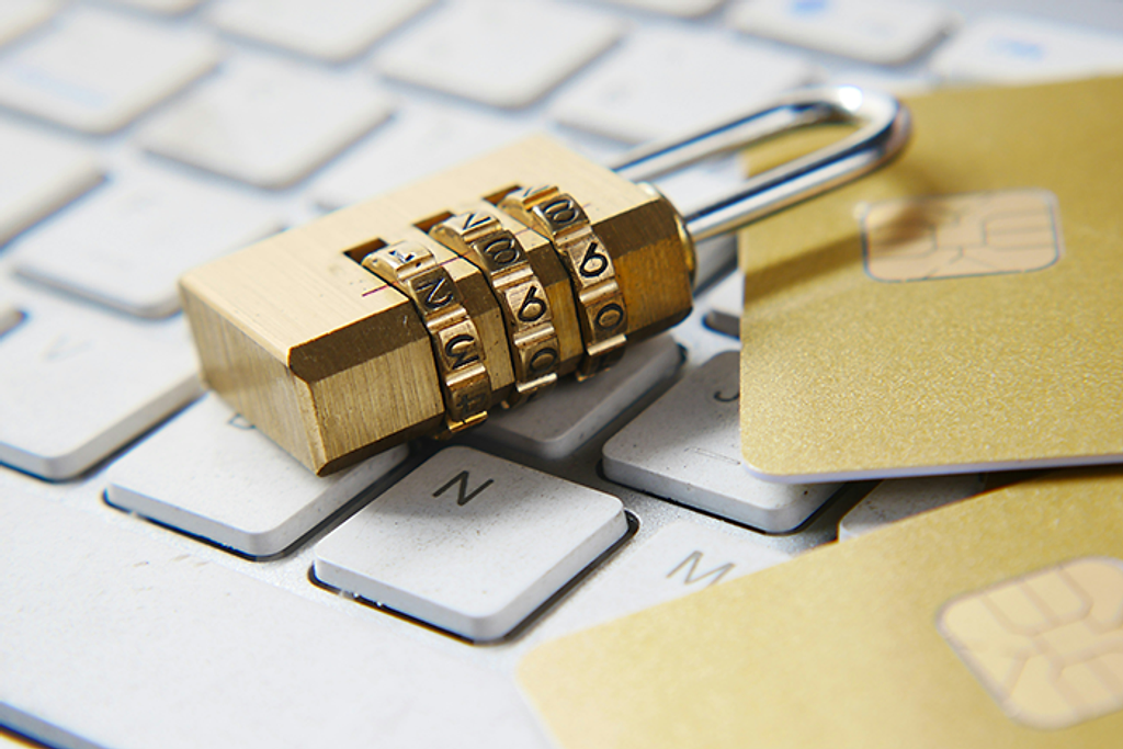 A combination padlock beside a payment card on a computer keyboard.