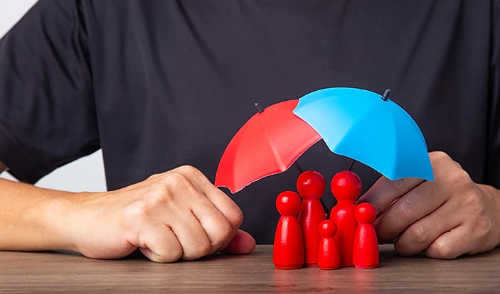 Miniature figures sheltered beneath a small multicoloured umbrella.