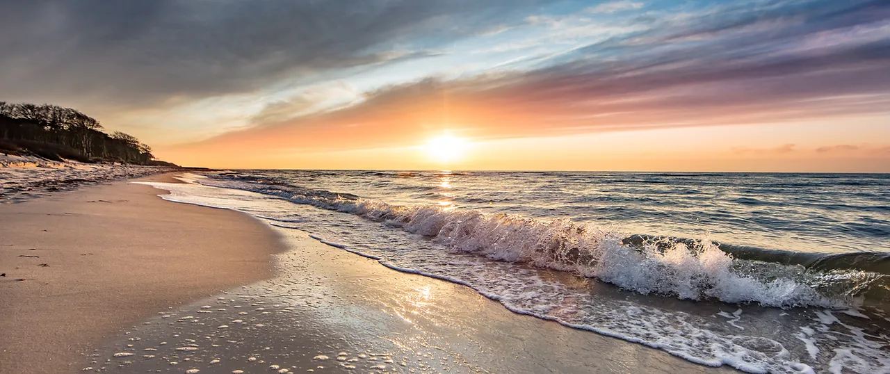 Sonnenaufgang am Ostseestrand mit Blick über Meer und Strand