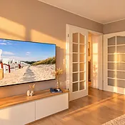 Wandmontierter Fernseher über der weißen Medienkommode im Wohnbereich