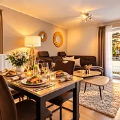 Festlich gedeckter Esstisch vor der Sofaecke im warmen Abendlicht