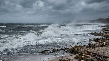 Herbststurm an der Ostseeküste mit aufgewühlter See und Gischt am leeren Strand