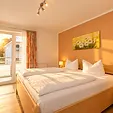 Schlafzimmer mit Doppelbett, Fernseher und Blick zum Balkon