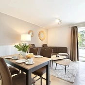 Offenes Wohnzimmer mit Couch, Esstisch und Küchenzeile