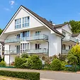 Appartementhaus der Ferienwohnung Helene mit Balkonen hinter grüner Hecke in der Straße Am Mönchgraben