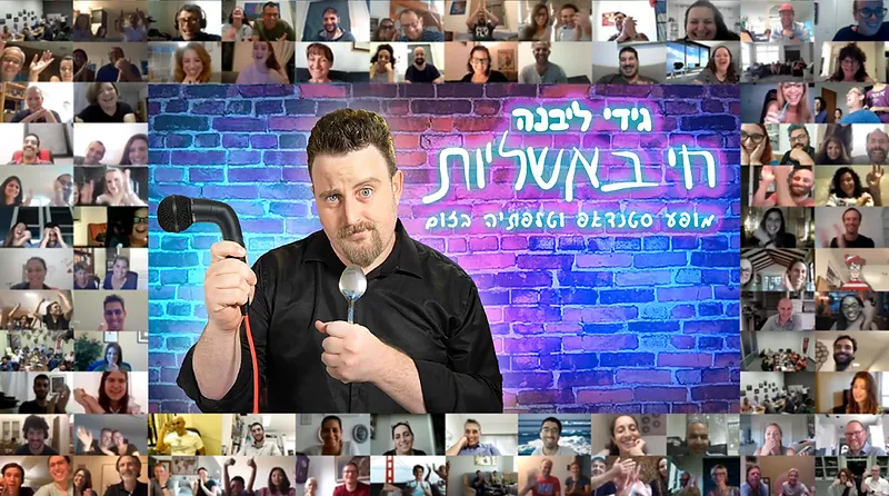 גידי ליבנה מחזיק מיקרופון וכף על רקע קיר לבנים עם צילומי מסך משיחת זום.