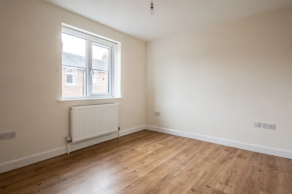 An empty room with laminate flooring and a white window