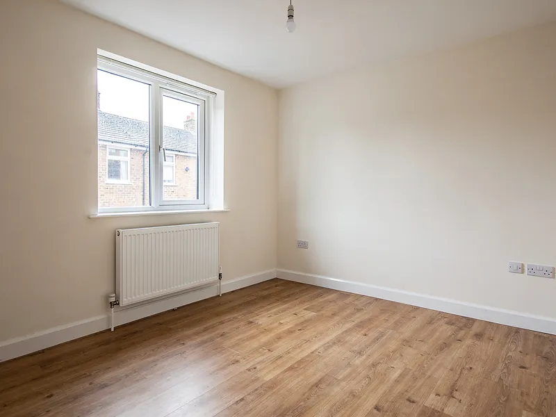 An empty room with laminate flooring and a white window