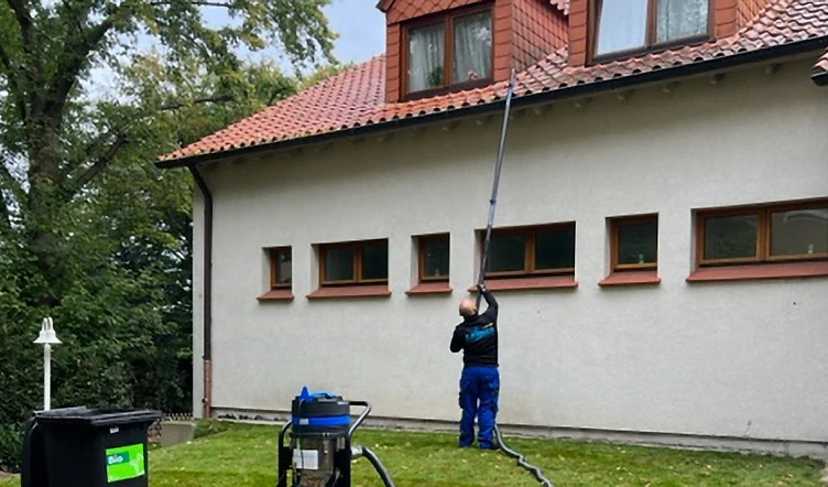 Dachrinnenreinigung mit der Teleskopstange am Wohnhaus