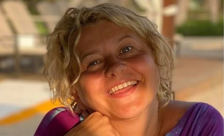 Kovács Andrea Tünde mosolyogva, virágmintás blúzban, természetes napfényben