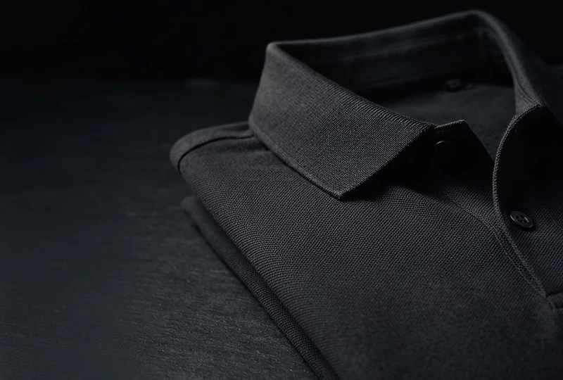 The two expressions of the House: a sculptural dark golf polo and an ivory bespoke formal shirt