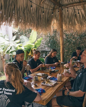 Communal outdoor dining table under a thatched roof